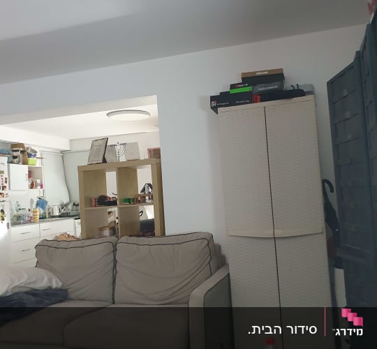 סלון עם ספה, ארון ומטבח ברקע